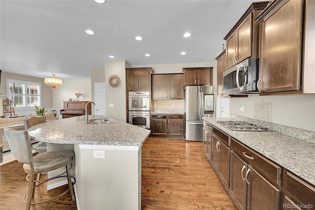 kitchen featuring an inviting chandelier, a breakfast bar, recessed lighting, a sink, and stainless steel appliances