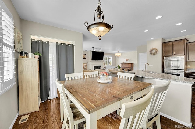 dining space with dark wood-style flooring, visible vents, a fireplace, baseboards, and recessed lighting