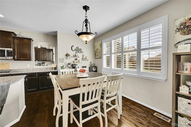 dining space with baseboards, visible vents, and dark wood-type flooring
