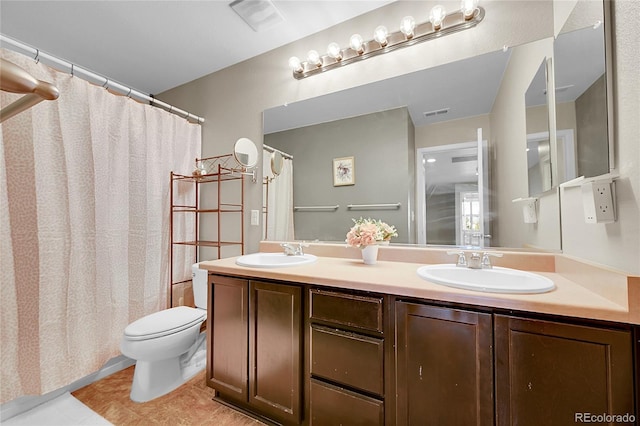 full bathroom featuring double vanity, toilet, a sink, and tile patterned flooring
