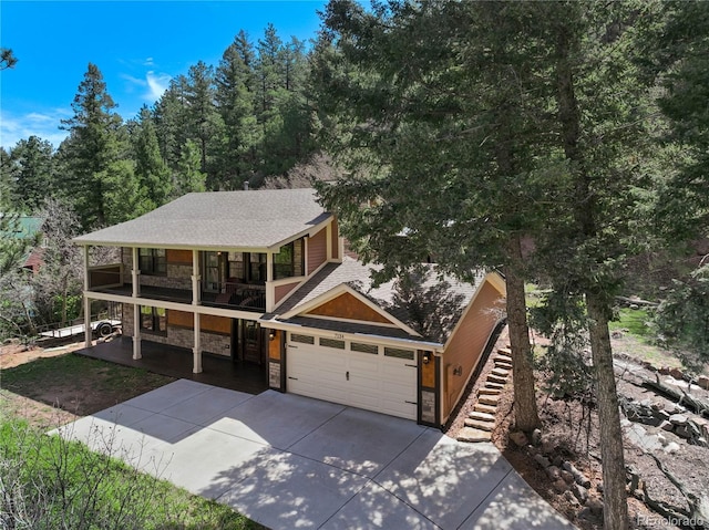 view of front of property with stone siding, a balcony, concrete driveway, a garage, and roof with shingles