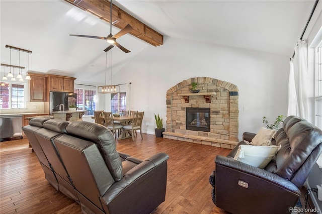 living room featuring ceiling fan, light wood finished floors, a fireplace, and a chandelier