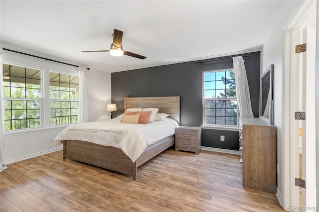 bedroom with wood finished floors, baseboards, and a ceiling fan