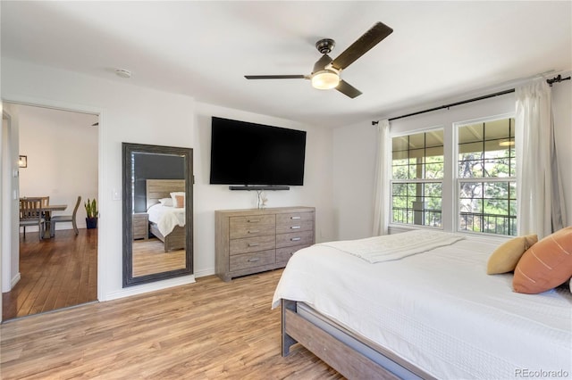 bedroom featuring light wood-type flooring, baseboards, and a ceiling fan