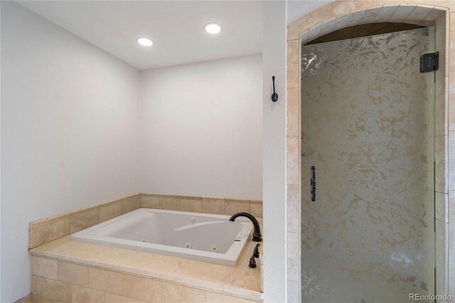 bathroom with a stall shower, a tub with jets, and recessed lighting