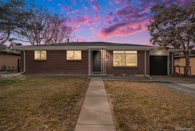 single story home with a front lawn, an attached garage, brick siding, and concrete driveway