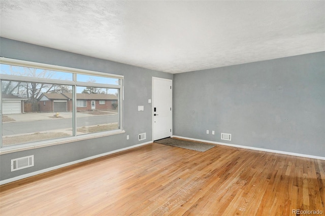 unfurnished room featuring wood finished floors, visible vents, and baseboards