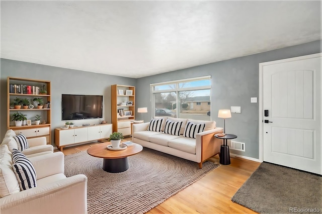 living room with visible vents, light wood-style floors, and baseboards