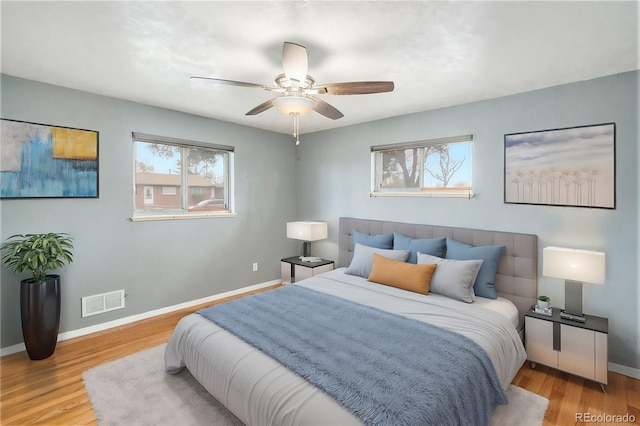 bedroom featuring visible vents, baseboards, wood finished floors, and a ceiling fan