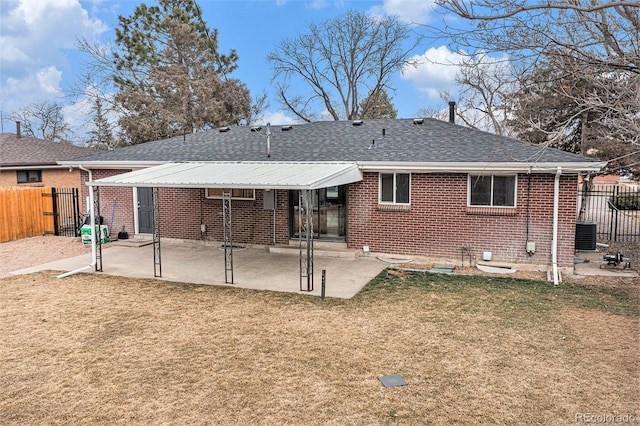 rear view of property featuring brick siding, fence, a lawn, and a patio area