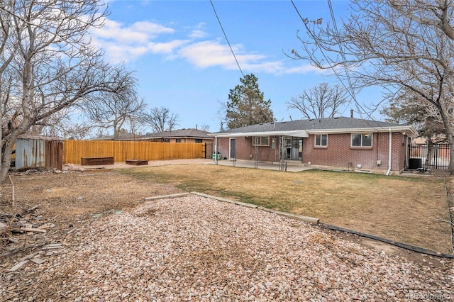 rear view of house featuring brick siding, central air condition unit, a fenced backyard, a yard, and a patio