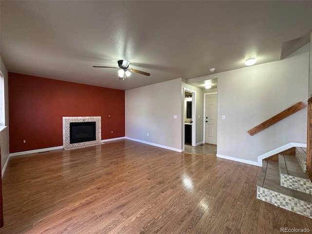 unfurnished living room featuring dark hardwood / wood-style floors, ceiling fan, and a fireplace