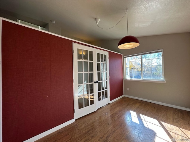 empty room with dark hardwood / wood-style floors, lofted ceiling, a textured ceiling, and french doors