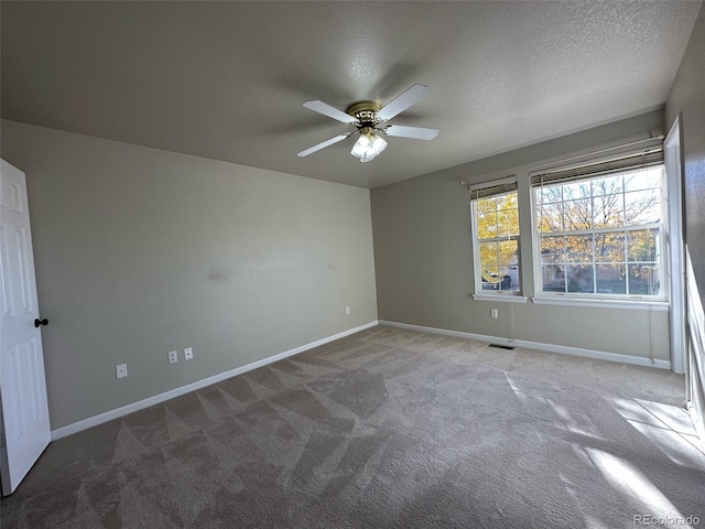 empty room featuring dark colored carpet, ceiling fan, and a textured ceiling