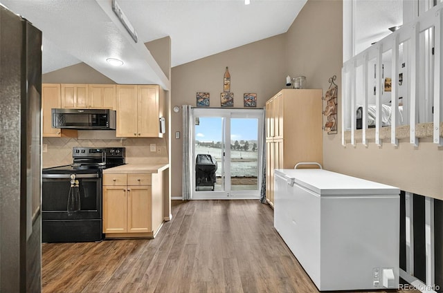 kitchen featuring black appliances, light brown cabinets, wood finished floors, tasteful backsplash, and high vaulted ceiling
