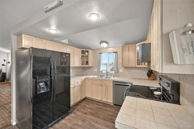 kitchen with black fridge, dishwasher, range with electric cooktop, a sink, and a textured ceiling