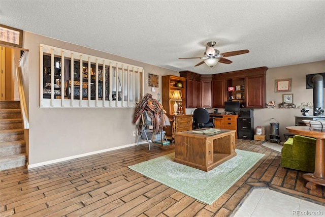 office space with ceiling fan, a textured ceiling, and a wood stove