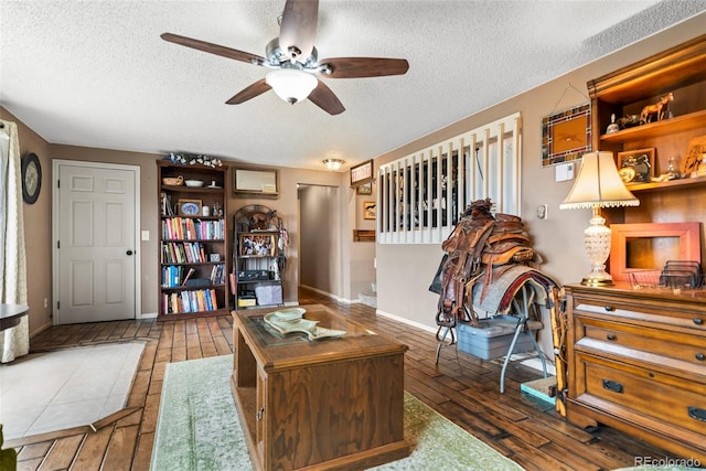 living area with hardwood / wood-style floors, a textured ceiling, and a ceiling fan