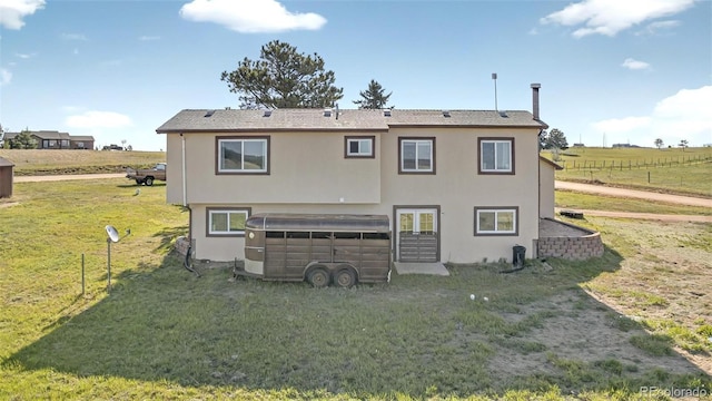 rear view of property featuring a yard, stucco siding, french doors, and a view of rural / pastoral area