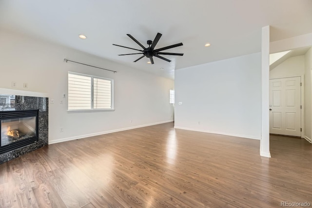 unfurnished living room featuring a premium fireplace, ceiling fan, and hardwood / wood-style flooring