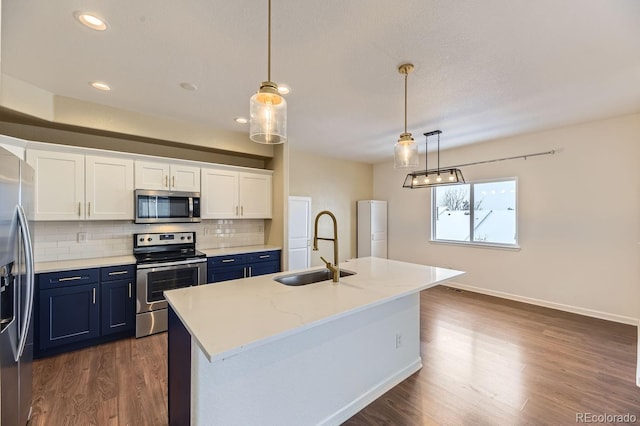 kitchen featuring appliances with stainless steel finishes, sink, pendant lighting, a center island with sink, and white cabinets