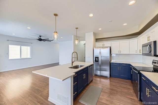 kitchen with blue cabinetry, white cabinetry, sink, stainless steel appliances, and an island with sink