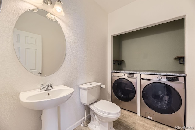 bathroom with tile patterned floors, washing machine and dryer, toilet, and sink