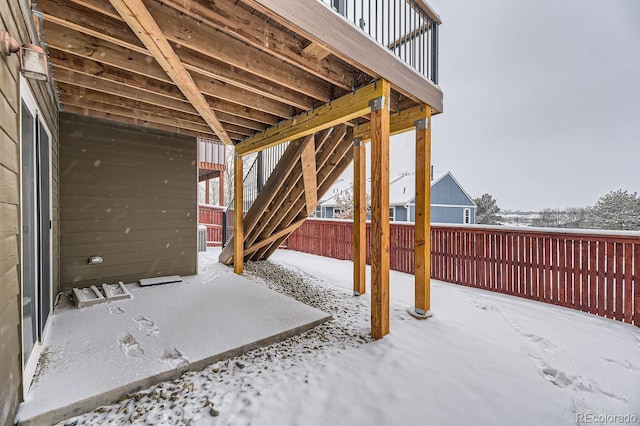 snow covered patio with a wooden deck