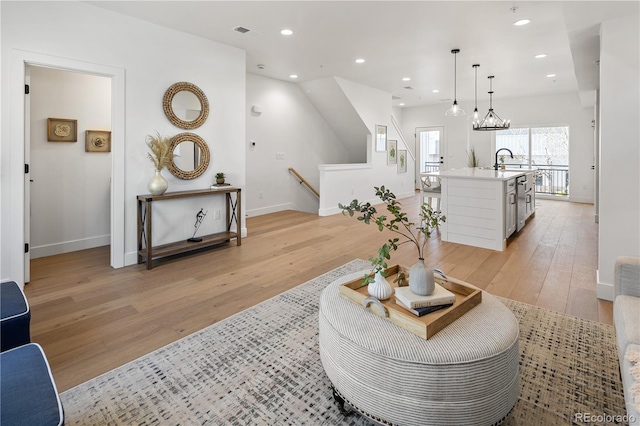 living room with baseboards, a chandelier, recessed lighting, light wood-style flooring, and visible vents