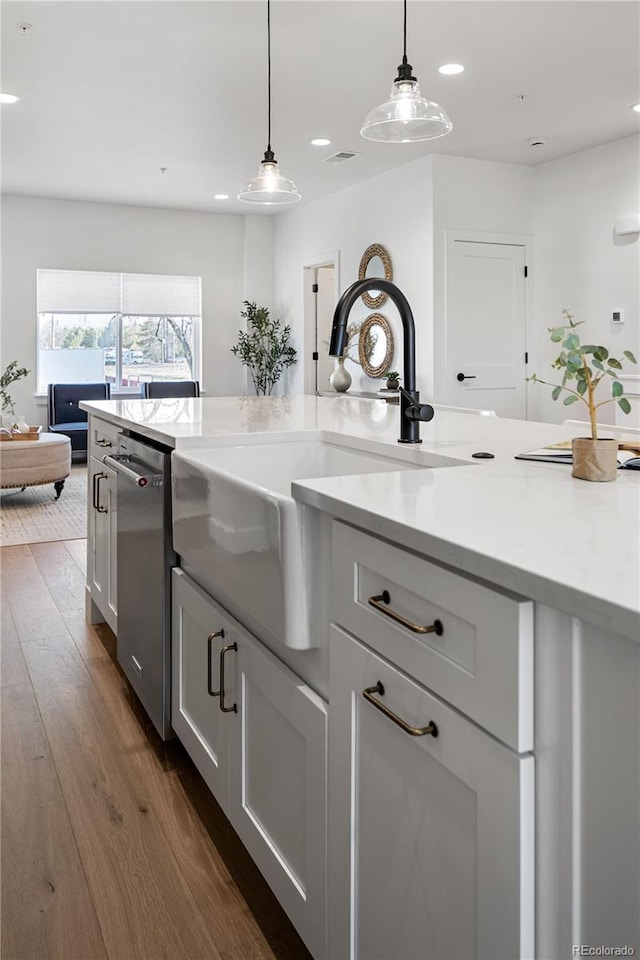 kitchen with hanging light fixtures, a sink, recessed lighting, dark wood-type flooring, and stainless steel dishwasher