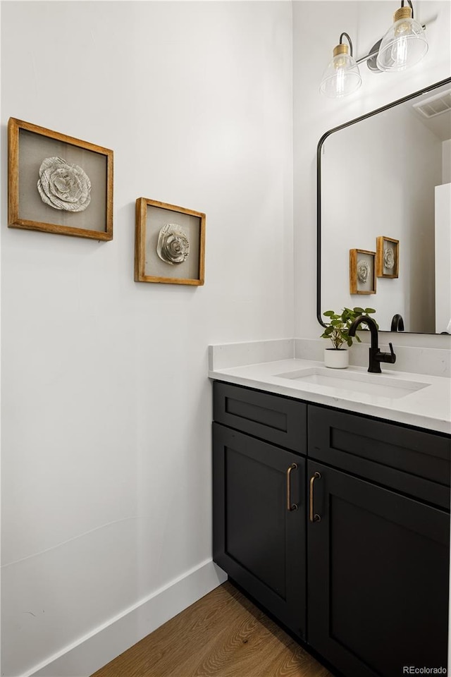 bathroom featuring visible vents, baseboards, vanity, and wood finished floors