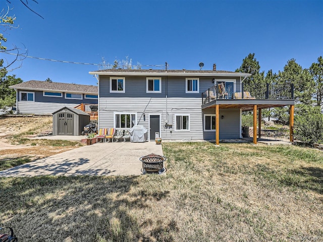 rear view of house featuring a patio, a lawn, a storage unit, a wooden deck, and a fire pit