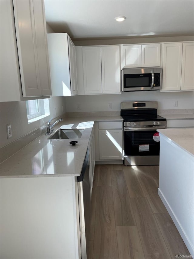 21996 E 39th Pl, Aurora, CO 80019 - kitchen with appliances with stainless steel finishes, a sink, wood finished floors, white cabinets, and light stone counters