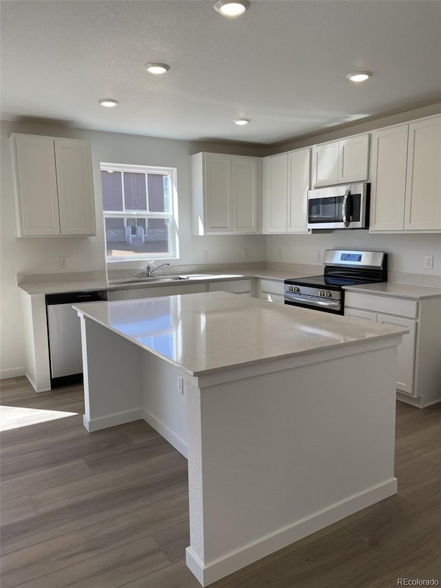 21996 E 39th Pl, Aurora, CO 80019 - kitchen with appliances with stainless steel finishes, a center island, white cabinetry, wood finished floors, and recessed lighting