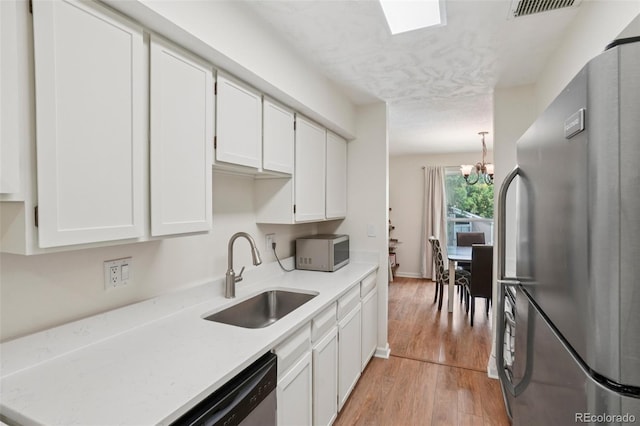 7305 S Xenia Cir Unit E, Centennial, CO 80112 - kitchen featuring appliances with stainless steel finishes, light wood-style flooring, white cabinets, a chandelier, and hanging light fixtures