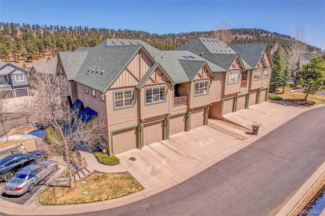 view of front of property featuring a shingled roof, board and batten siding, driveway, and a garage