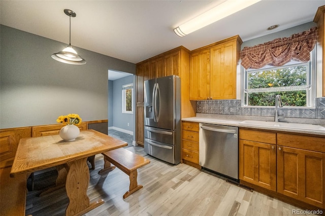 kitchen with backsplash, sink, stainless steel appliances, and light wood-type flooring