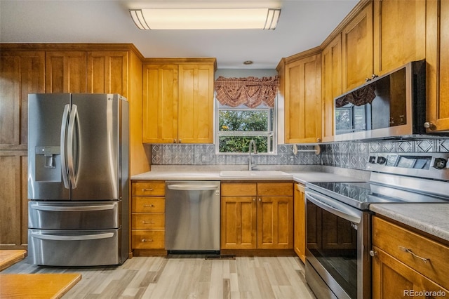 kitchen with light hardwood / wood-style flooring, decorative backsplash, stainless steel appliances, and sink