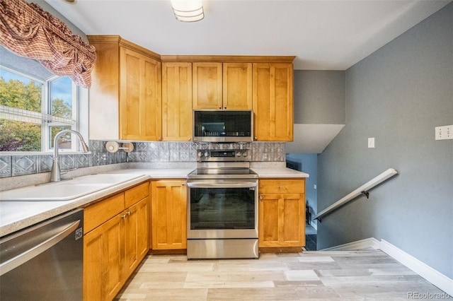 kitchen featuring sink, appliances with stainless steel finishes, decorative backsplash, and light hardwood / wood-style flooring