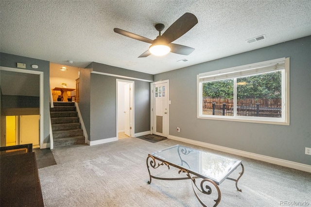 living area featuring ceiling fan, carpet, and a textured ceiling