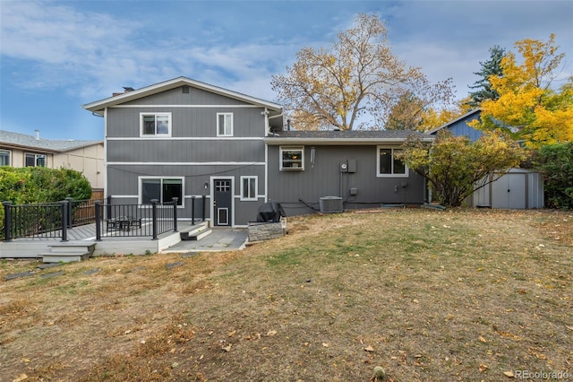 back of house featuring a yard, a storage shed, a wooden deck, and central air condition unit