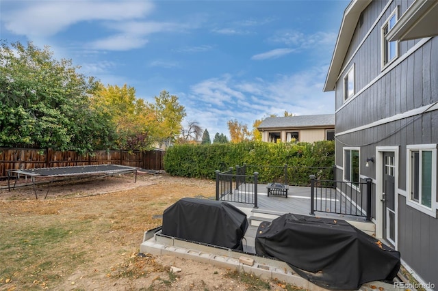 view of yard featuring a wooden deck and a trampoline