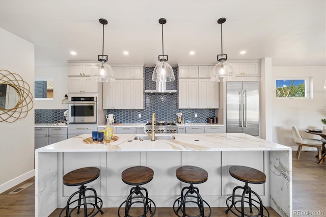 2010 Irving St, Denver, CO 80211 - kitchen with appliances with stainless steel finishes, decorative backsplash, dark wood-style flooring, a center island with sink, and wall chimney range hood