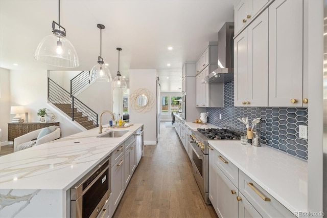 2010 Irving St, Denver, CO 80211 - kitchen with stainless steel appliances, wall chimney range hood, wood finished floors, a center island with sink, and decorative backsplash