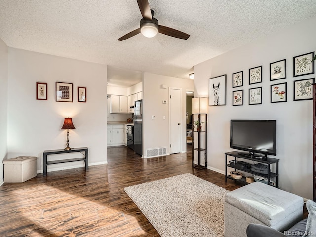 living room featuring baseboards, visible vents, ceiling fan, dark wood-style flooring, and a textured ceiling