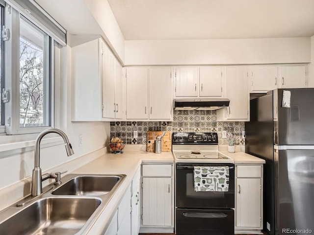 kitchen with range with electric stovetop, light countertops, freestanding refrigerator, a sink, and under cabinet range hood