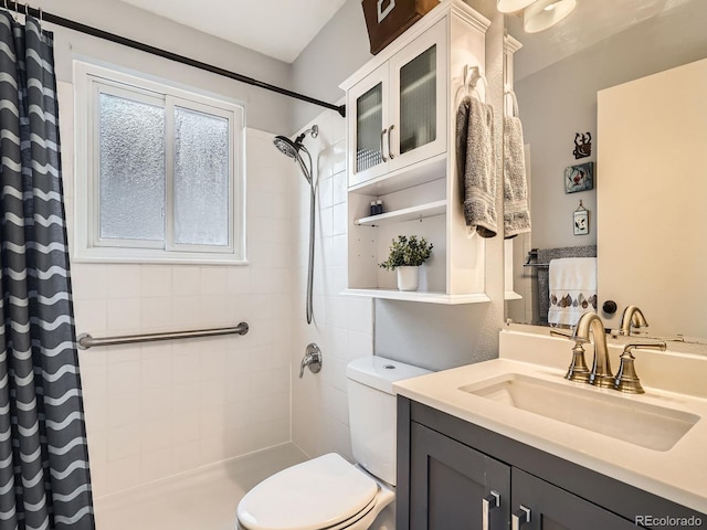 full bathroom featuring a tile shower, vanity, and toilet