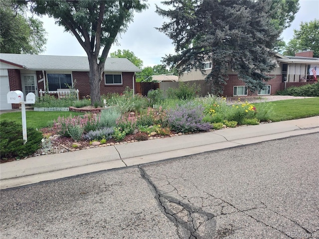 view of front of property featuring brick siding, a front lawn, and fence