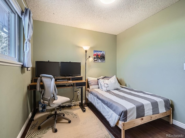 bedroom featuring a textured ceiling, baseboards, and wood finished floors