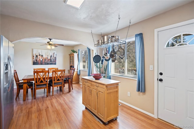 kitchen featuring a center island, light brown cabinets, light wood-type flooring, stainless steel fridge, and ceiling fan with notable chandelier